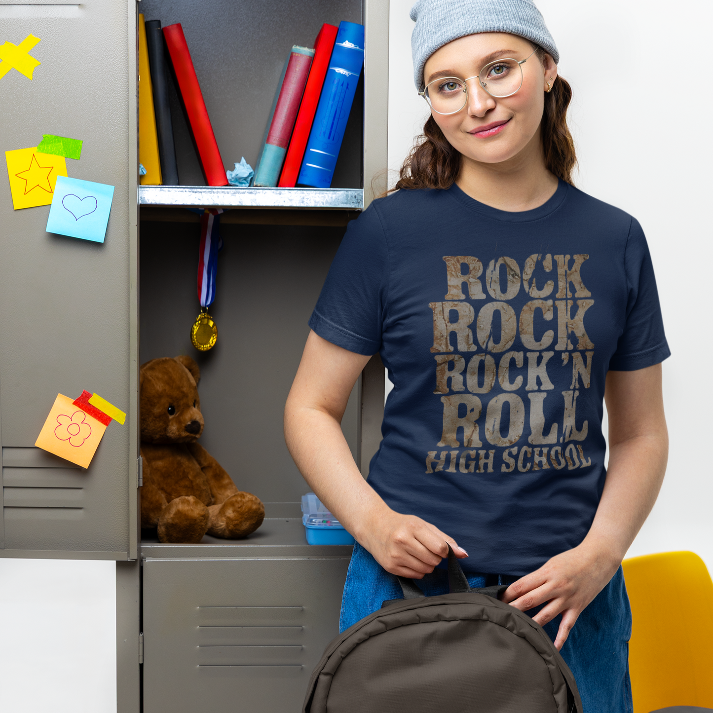 Person wearing a 'Rock Rock Rock N Roll High School' t-shirt holding a backpack in front of a locker.