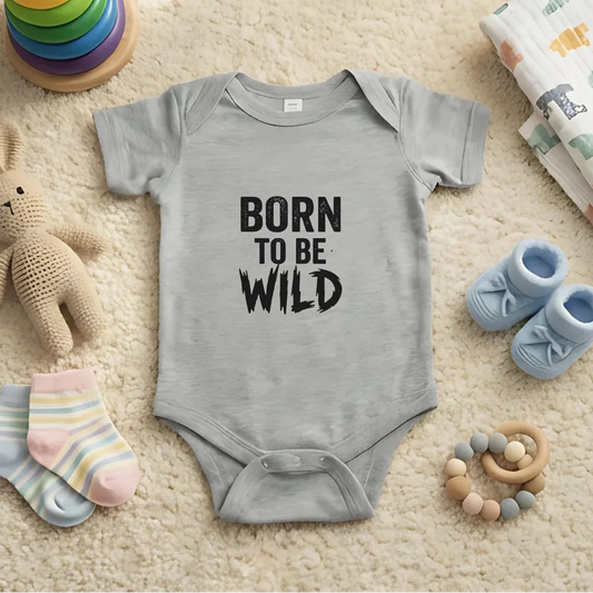 Gray baby onesie with 'Born to be Wild' text on a carpeted floor with toys around