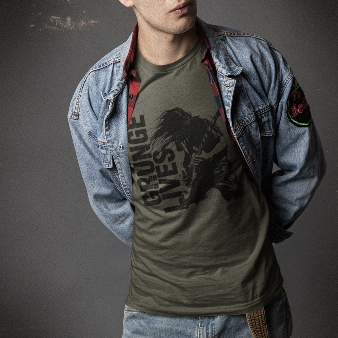 Person wearing a denim jacket and green graphic t-shirt against a dark background